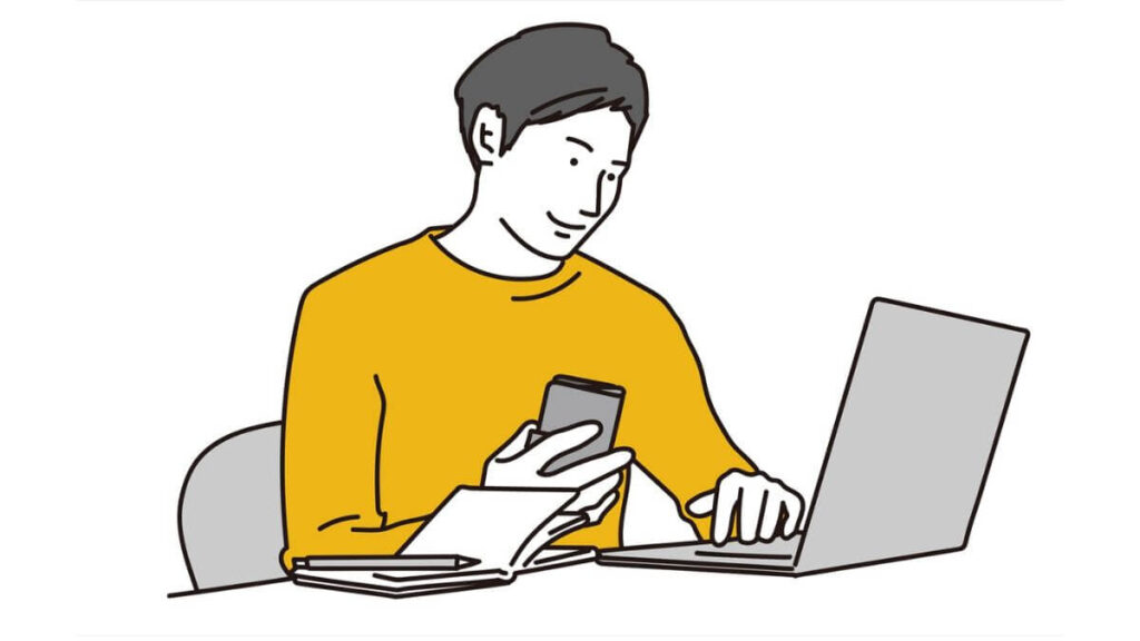 パソコンとスマホを使い仕事をする男性