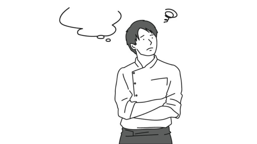 腕を組み考え事をする料理人の男性