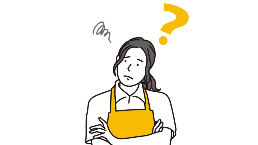 腕を組み考えるエプロン姿の女性
