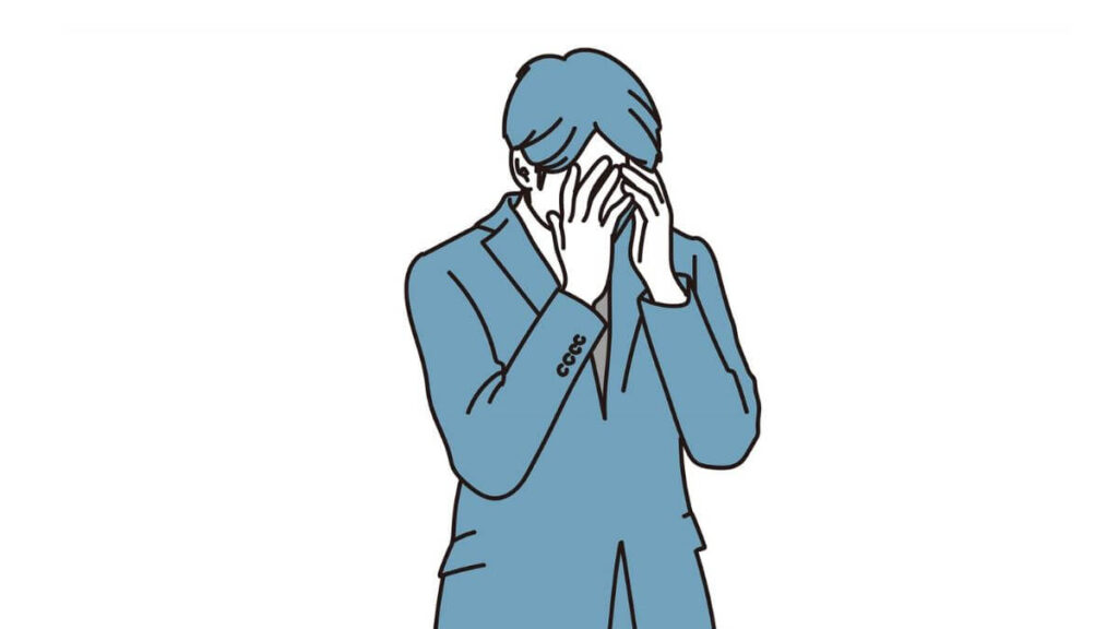 両手で顔を覆い悩むスーツ姿の男性