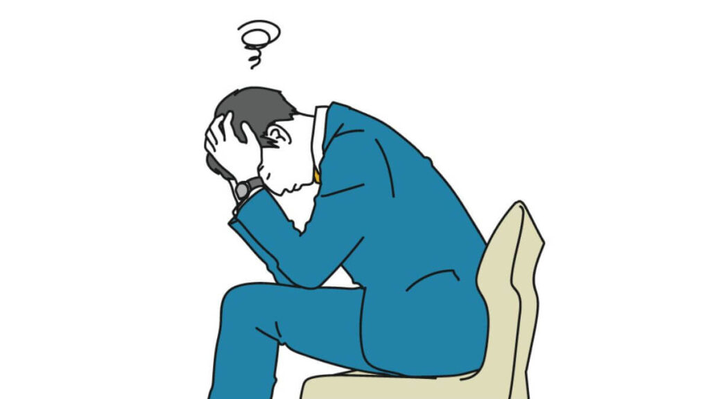 椅子に座り頭を抱えるスーツ姿の男性