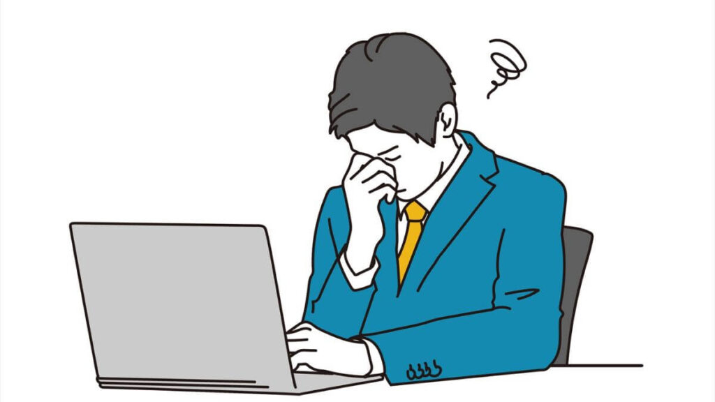 パソコン前で疲れて目頭を抑えるスーツ姿の男性