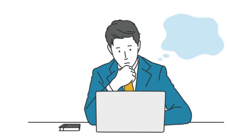 考え事をしながらパソコンを使うスーツ姿の男性