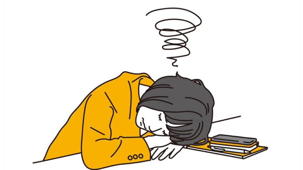 机にふせ悩む若い女性