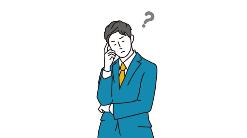 人差し指を頬に置き考え事をするスーツ姿の男性