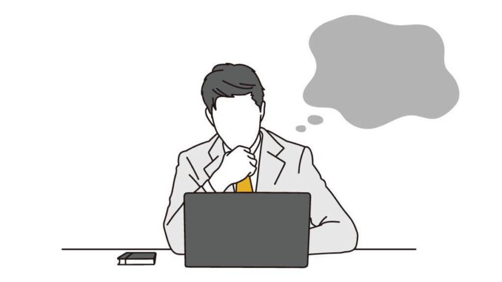 考え事をしながらパソコン仕事をするスーツの男性
