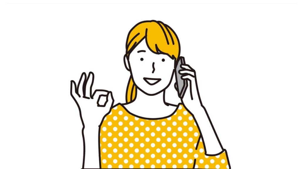 電話をしながらOKサインをする若い女性