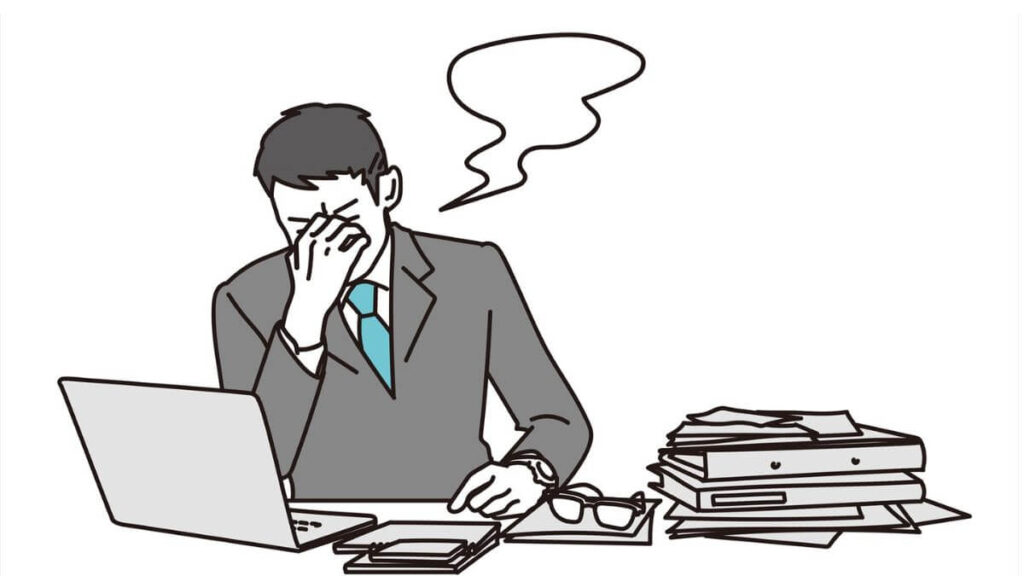 職場で目を抑え疲れているスーツ姿の男性