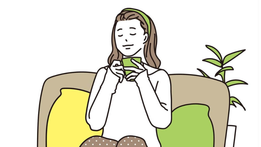 ソファーに座り穏やかに飲み物を飲む女性