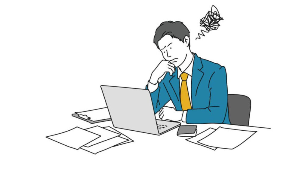 困った表情をしながら仕事をするスーツ姿の男性