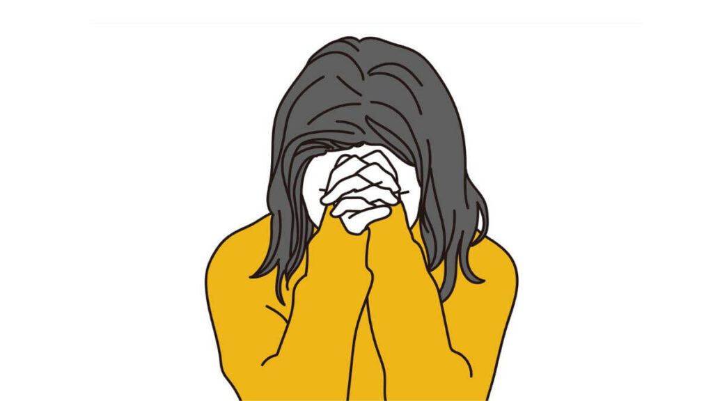 手を組み頭を抱える若い女性