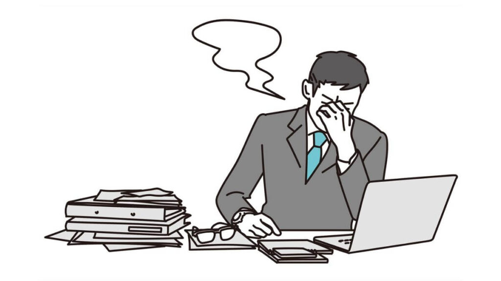 デスクの前で目頭を抑えるサラリーマンの男性