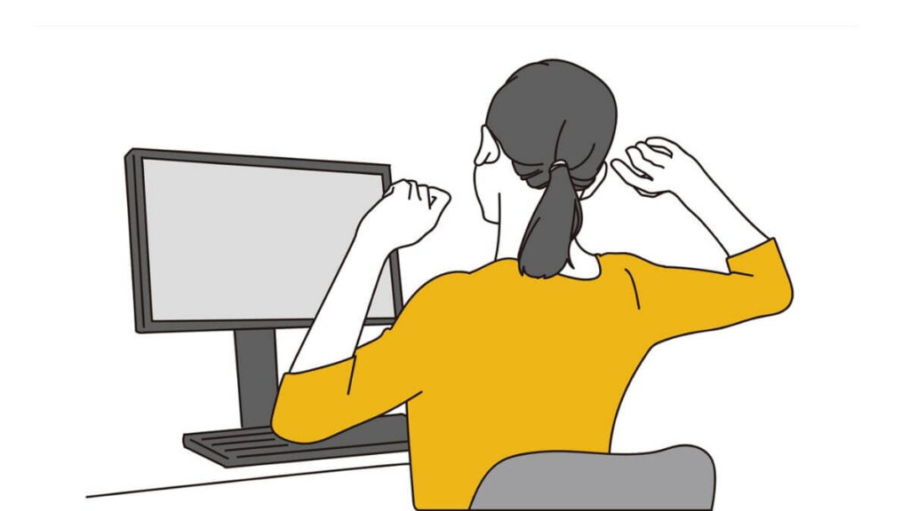 パソコン作業中に伸びをする若い女性