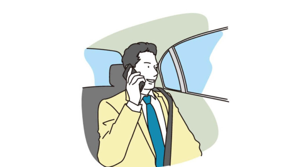 車の中で笑顔で電話をするスーツ姿の男性