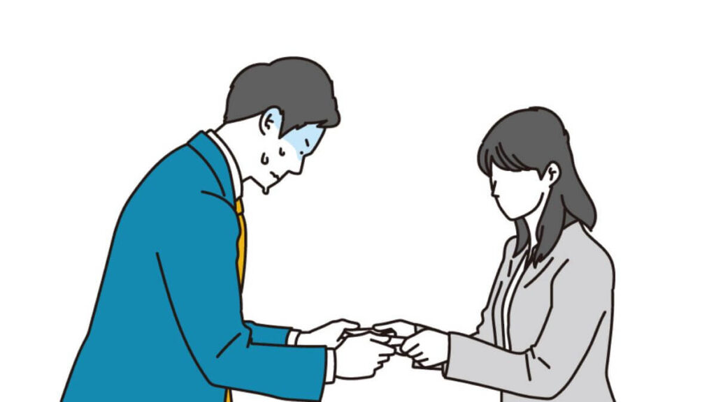 緊張しながら名刺交換をするスーツ姿の男性