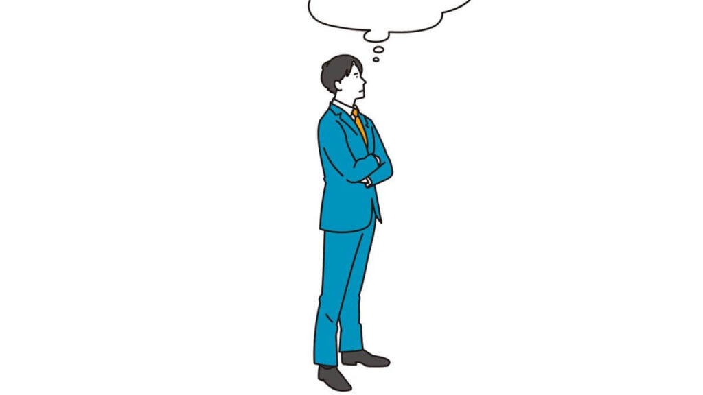 腕を組み困った表情をするスーツ姿の男性