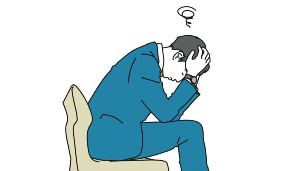 椅子に座り頭を抱えるサラリーマンの男性