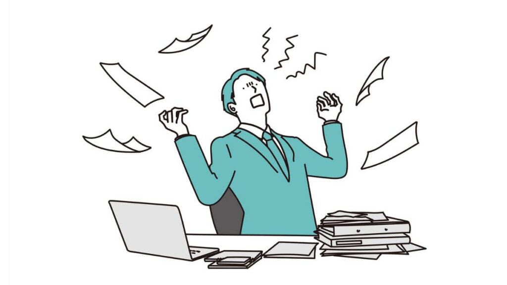 書類が散らばったデスクで仕事をする男性