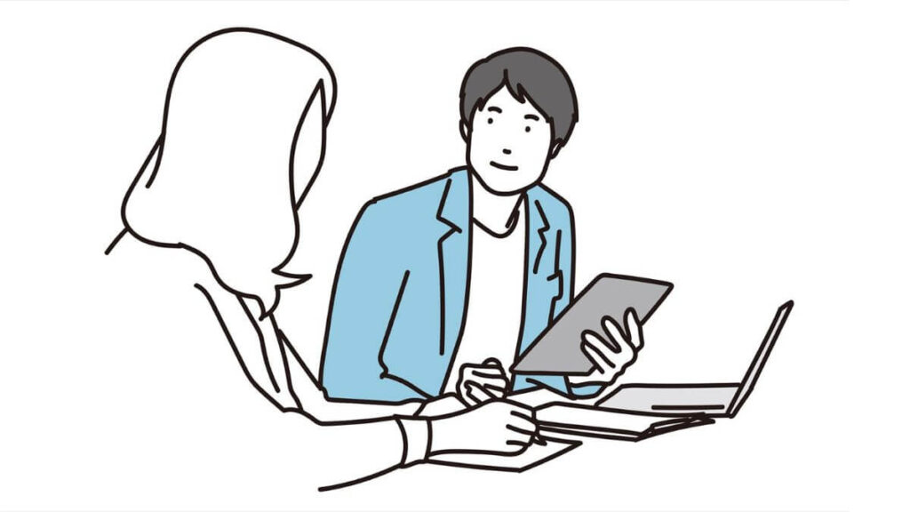 タブレットを片手に同僚と話す若い男性