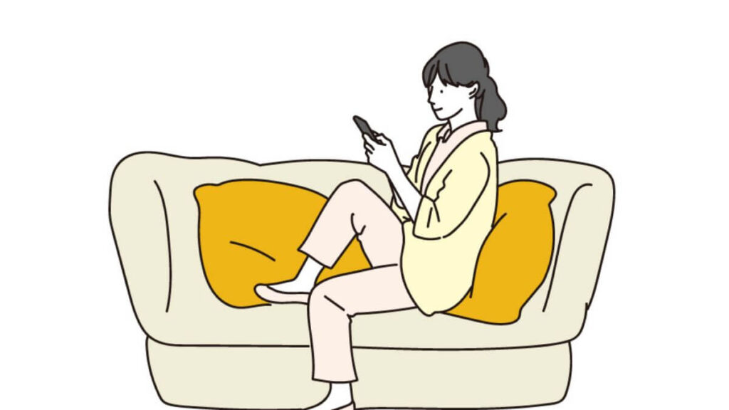 ソファーでスマホを使う若い女性