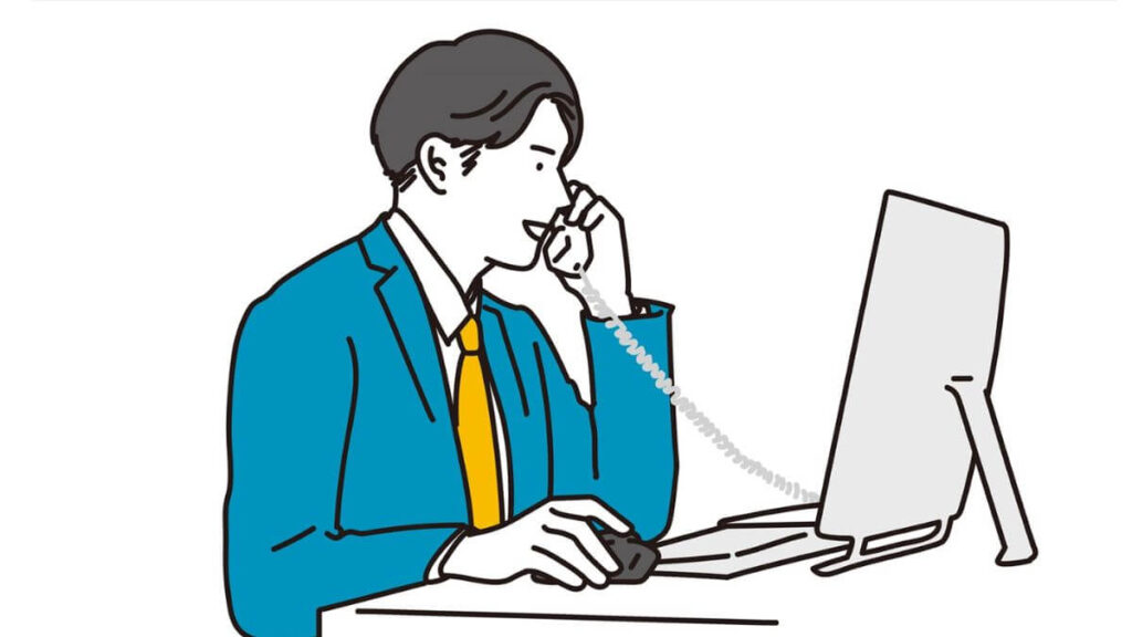 パソコンと電話を使い仕事をこなすスーツ姿の男性