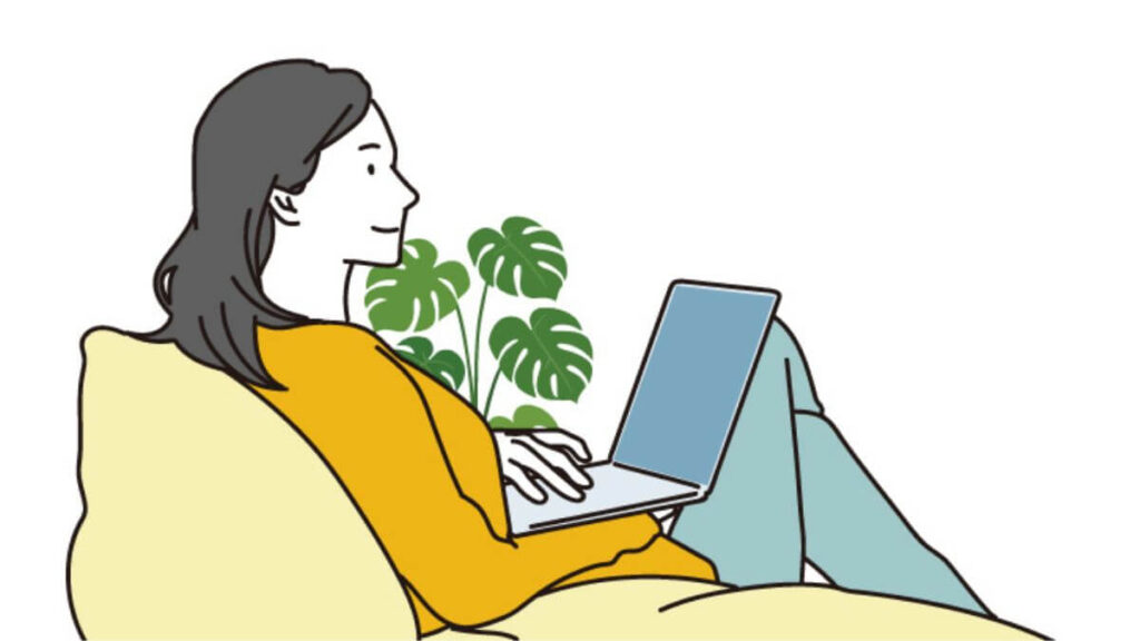 ソファーに座り優雅にパソコン作業をする女性