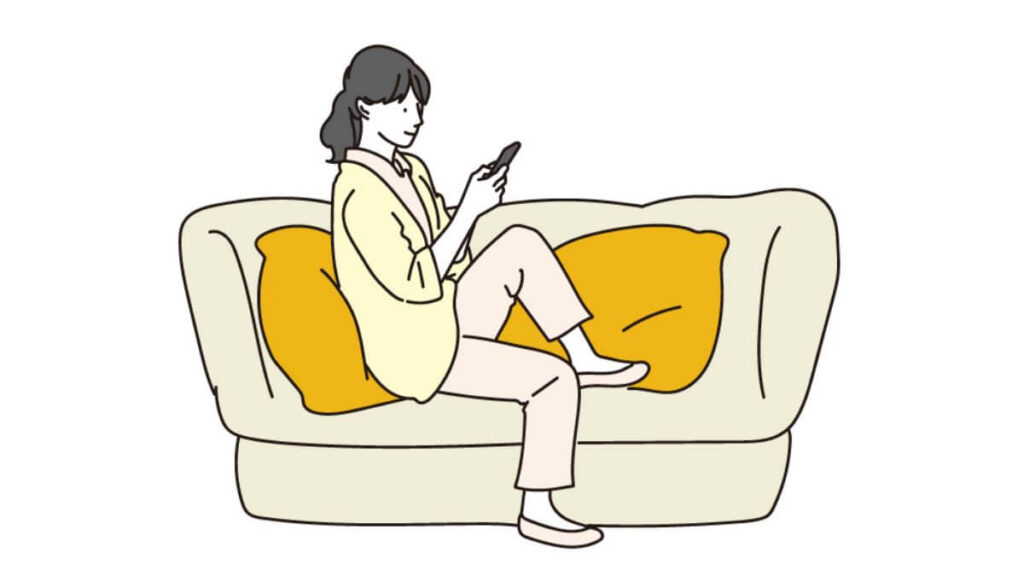 ソファーに座ってスマホを触る若い女性