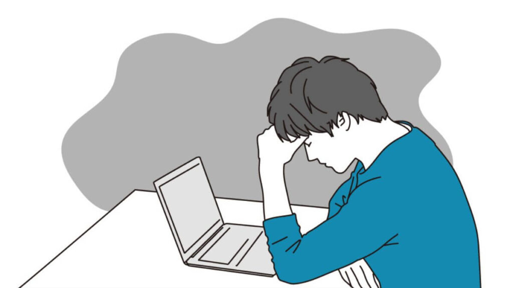 パソコンの前でつらそうな表情をする若い男性