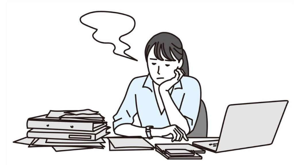 机の前で肘をつき不満そうな表情をするキャリアウーマン